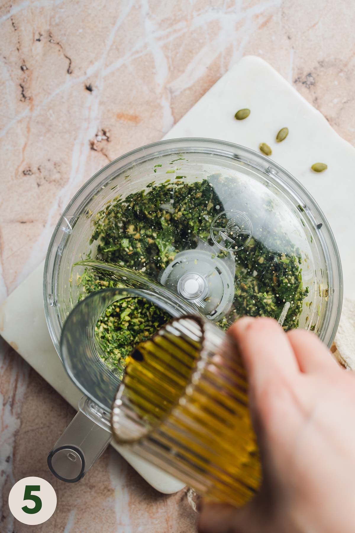 Olive oil being drizzled into the food processor