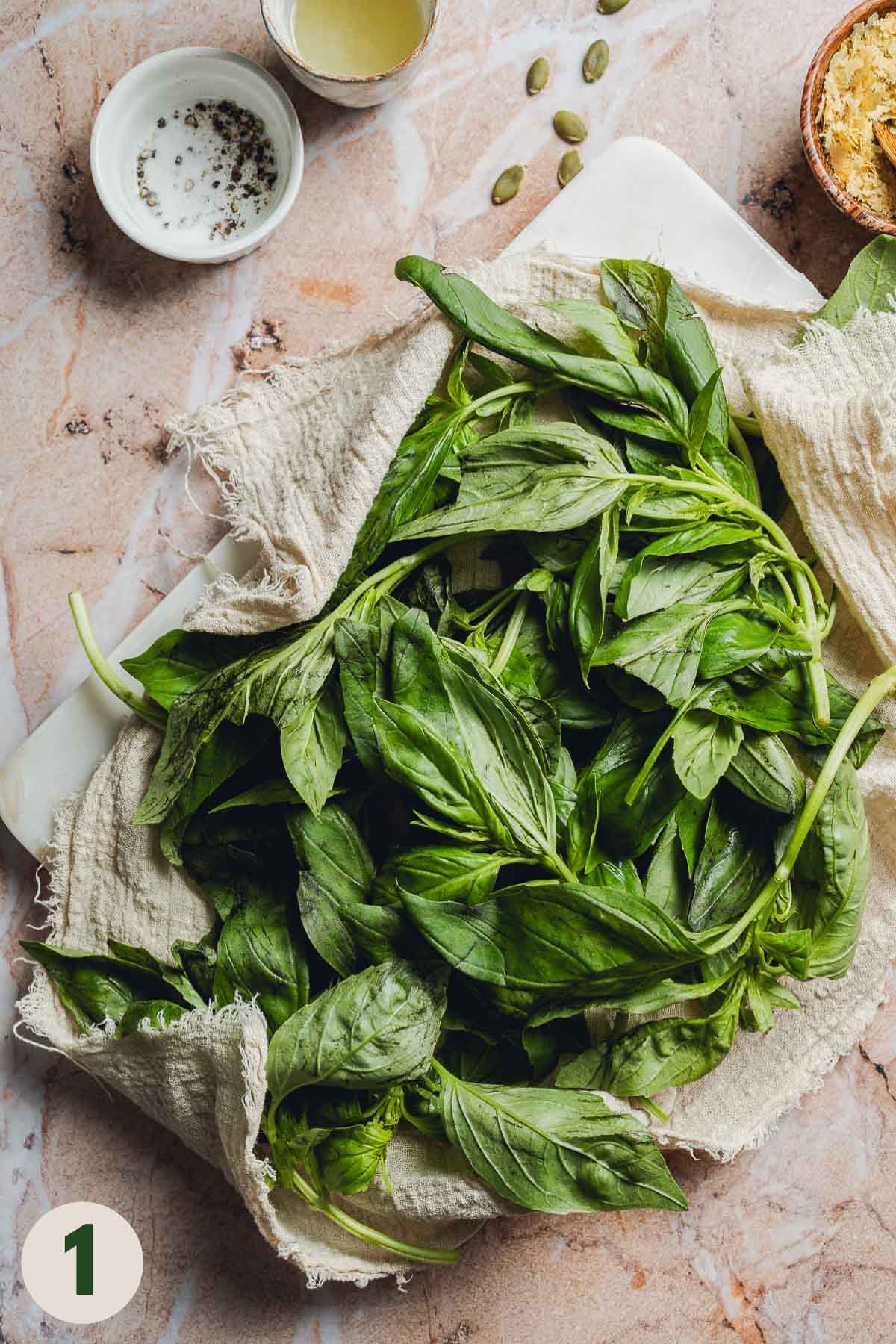 Fresh basil leaves and stems on a linen cloth.