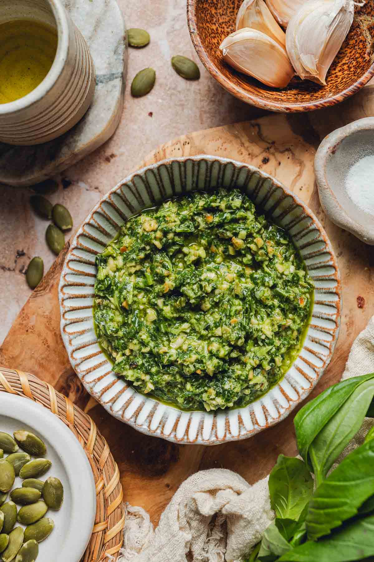 A small bowl of green pumpkin seed pesto on a wooden board