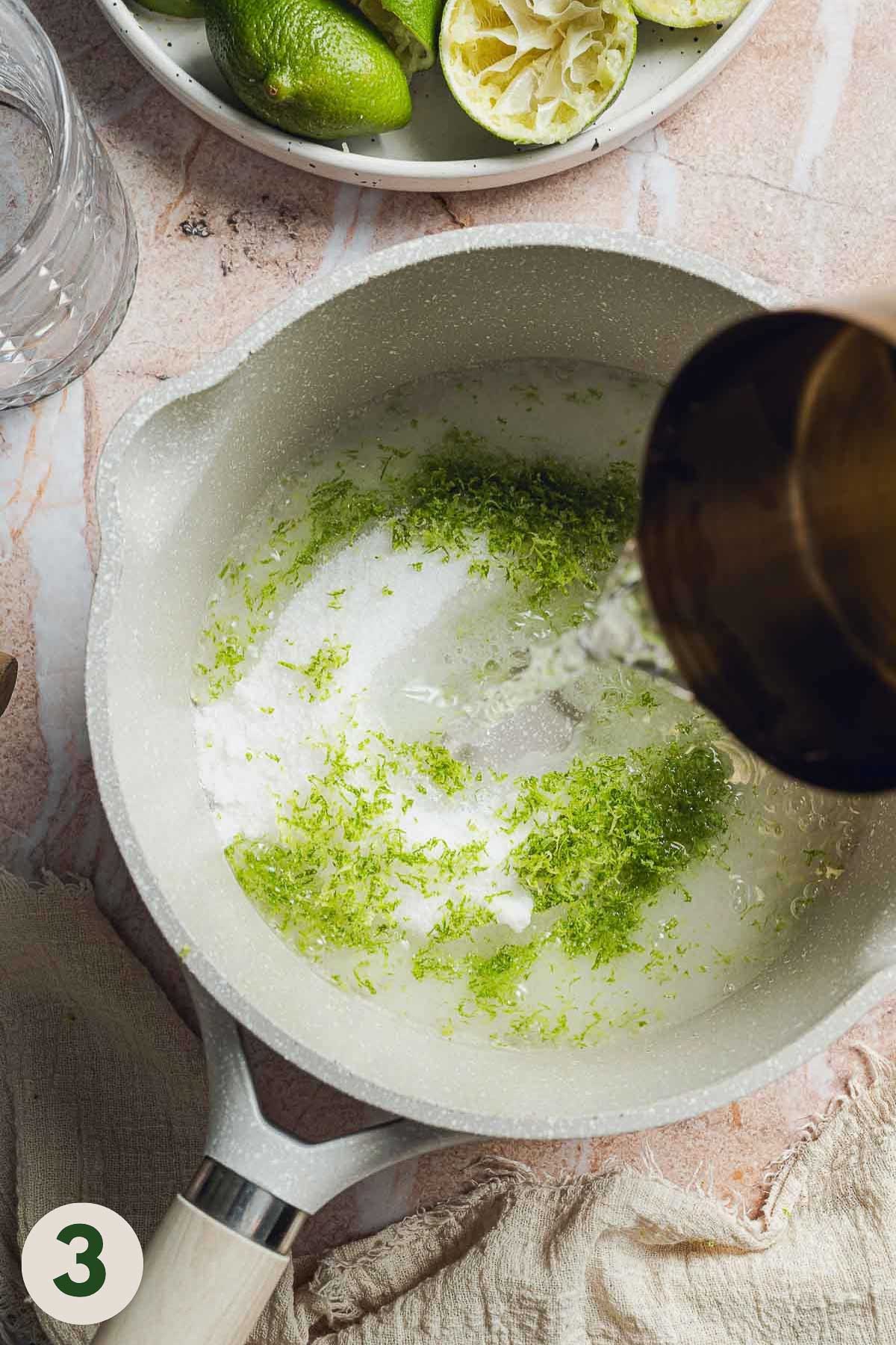 Water being poured into a pan of sugar and lime zest